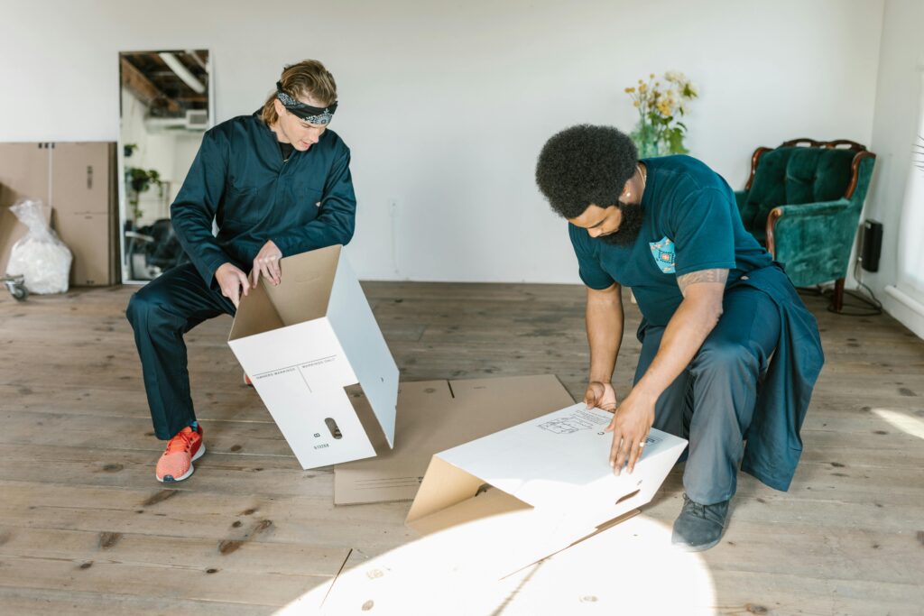 Two men assembling cardboard boxes indoors, preparing for moving.