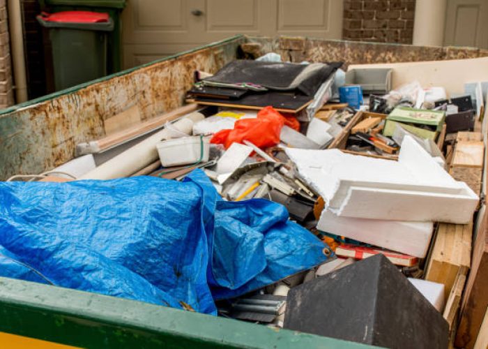 Container voll mit Sperrmüll vor einem Haus